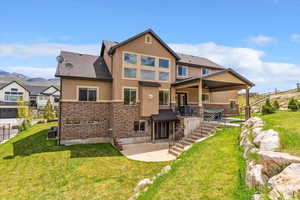 Rear view of house with stucco siding, a patio area, stairway, and a mountain view