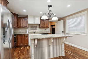 Kitchen featuring stainless steel fridge with ice dispenser, baseboards, dark wood finished floors, light stone countertops, and recessed lighting