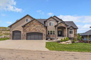 View of front facade with stucco siding, stone siding, and driveway