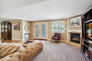 Living room with a high end fireplace, recessed lighting, baseboards, a textured ceiling, and carpet floors