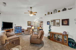 Living room with lofted ceiling, a ceiling fan, and light tile patterned floors