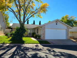 View of front facade featuring a garage, concrete driveway, stucco siding, stone siding, and a front lawn