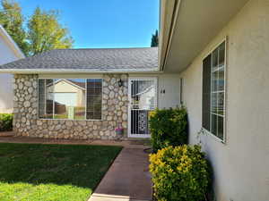 Entrance to property with stucco siding and roof with shingles