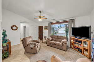 Living area featuring vaulted ceiling, ceiling fan, and light tile patterned floors