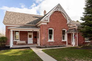 View of front of property with brick siding, a chimney, a front yard, and a shingled roof