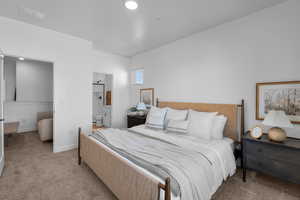 Bedroom featuring light carpet, ensuite bath, and baseboards
