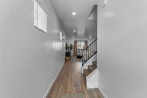 Hallway featuring baseboards, stairway, and wood finished floors