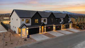 View of front of home featuring a garage, stucco siding, driveway, a mountain view, and fence