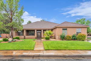 View of front of house with stone siding, a front yard, stucco siding, and a tile roof