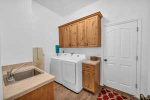 Laundry area featuring cabinet space, separate washer and dryer, and light wood-type flooring