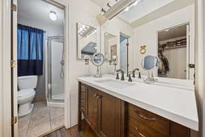 Full bath featuring toilet, a shower stall, vanity, and wood finished floors