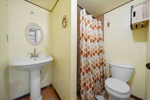 Bathroom with toilet, tile patterned flooring, baseboards, and a shower with curtain