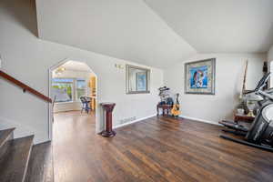 Exercise room with wood finished floors, lofted ceiling, baseboards, and arched walkways
