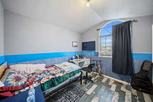Bedroom with hardwood / wood-style floors, lofted ceiling, and a textured ceiling