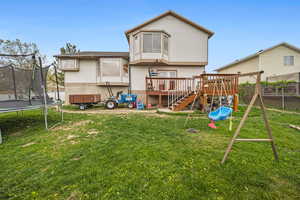 Back of property featuring a trampoline, a wooden deck, a playground, and stairway
