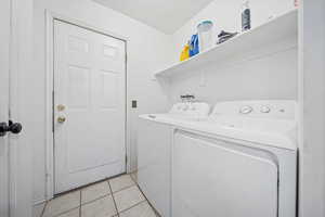 Laundry room with separate washer and dryer and light tile patterned floors