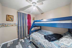 Bedroom featuring wood finished floors, baseboards, ceiling fan, and a textured ceiling