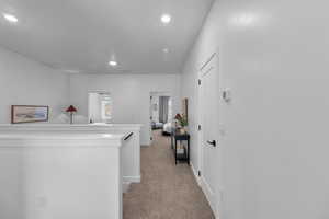 Hallway with light carpet, recessed lighting, baseboards, and an upstairs landing