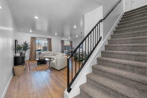 Stairs with wood finished floors, recessed lighting, and baseboards