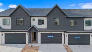 Townhome / multi-family property featuring a garage, stucco siding, and driveway