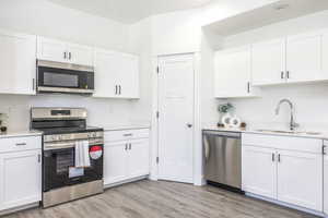 Kitchen featuring appliances with stainless steel finishes, a sink, light countertops, and white cabinets