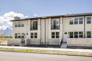 View of front facade featuring a balcony, stone siding, stucco siding, a mountain view, and entry steps