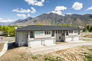 View of front facade featuring a garage, stucco siding, a balcony, a mountain view, and concrete driveway
