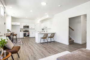 Kitchen featuring stainless steel appliances, light wood-style floors, white cabinetry, and recessed lighting