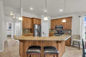Kitchen featuring stainless steel appliances, brown cabinets, baseboards, and light tile patterned floors