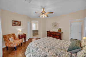 Bedroom featuring hardwood / wood-style floors, baseboards, ceiling fan, and connected bathroom