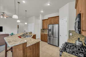 Kitchen with black appliances, a sink, open floor plan, brown cabinetry, and decorative backsplash