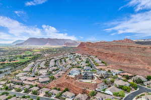 Aerial view of property and surrounding area featuring a mountainous background and nearby suburban area