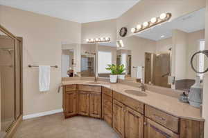 Bathroom with a shower stall, tile patterned floors, baseboards, and double vanity