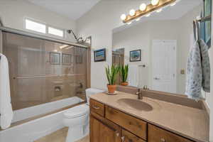 Bathroom with tile patterned flooring, toilet, vanity, and enclosed tub / shower combo