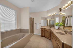 Bathroom featuring a garden tub, a shower stall, tile patterned floors, and double vanity