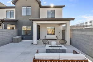 Back of house featuring stucco siding, a patio area, a fenced backyard, and an outdoor living space with a fire pit