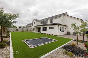 Rear view of property featuring a trampoline, central AC unit, stucco siding, and a patio