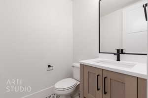 Bathroom with toilet, vanity, and baseboards