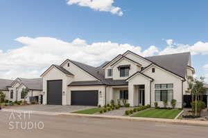 Modern farmhouse featuring an attached garage, board and batten siding, decorative driveway, and fence