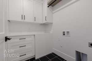 Clothes washing area featuring electric dryer hookup, cabinet space, dark tile patterned floors, hookup for a washing machine, and baseboards