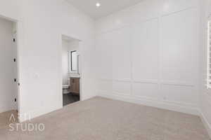 Unfurnished bedroom featuring carpet floors, connected bathroom, a decorative wall, and recessed lighting