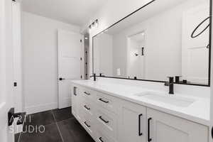 Bathroom with double vanity, tile patterned flooring, and baseboards