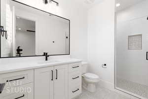 Full bathroom featuring toilet, tiled shower, and vanity