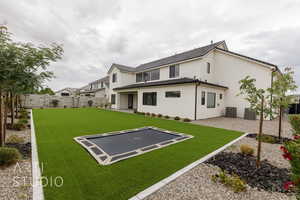 Back of property with a trampoline, a patio area, stucco siding, and cooling unit