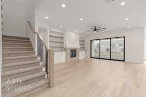 Unfurnished living room featuring recessed lighting, a ceiling fan, baseboards, stairway, and light wood-style flooring