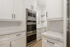 Kitchen featuring stainless steel appliances, tasteful backsplash, and white cabinets