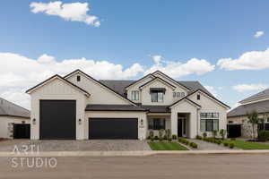 Modern farmhouse style home featuring an attached garage, decorative driveway, board and batten siding, and fence