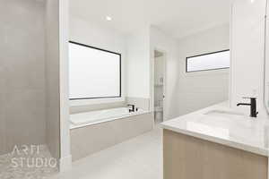 Bathroom with toilet, a bath, double vanity, and tile patterned floors