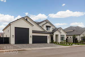 Modern inspired farmhouse featuring a garage, board and batten siding, decorative driveway, brick siding, and fence
