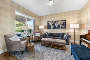 Living room featuring wallpapered walls, baseboards, and wood finished floors